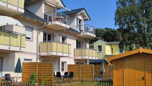 Ein mehrstöckiges Wohnhaus mit Balkonen, einem Holzzaun und einer kleinen Holzhütte.