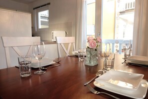 A dining table set with white plates, cutlery, and glasses, with a vase of pink flowers. - 3-zi-fewo für 4 Pers. mit Wlan, Strandnah (Graal-Müritz)
