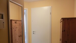 Un pasillo con una puerta de madera, una puerta blanca y un armario de madera.