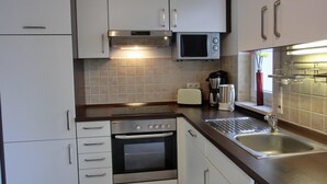 A compact kitchen with white cabinets, a microwave, a toaster, a coffee maker, and a sink.