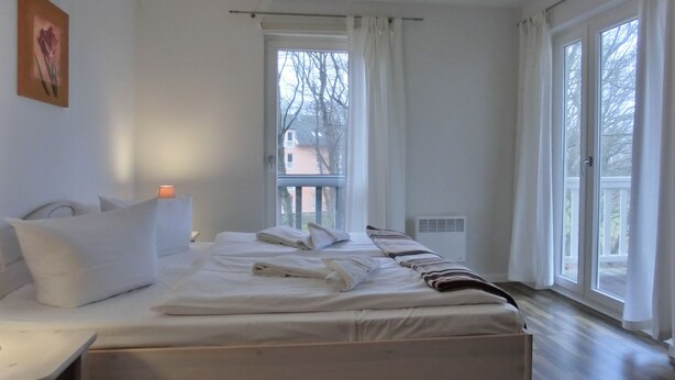 A bedroom with a bed, a bedside table, a window, and a radiator. - 4-zi-fewo für 6 Pers.im 2.og, Wlan, Strandnah (Graal-Müritz)