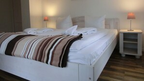 A neatly made bed with white linens and a striped blanket, two bedside tables with lamps, and a framed picture on the wall. - 4-zi-fewo für 6 Pers.im 2.og, Wlan, Strandnah (Graal-Müritz)