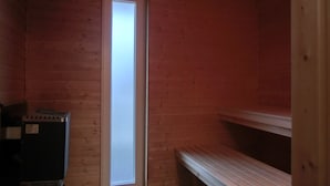 A small, dimly lit room with wooden walls, a single bench, and a small heater. - 4-zi-fewo für 6 Pers.im 2.og, Wlan, Strandnah (Graal-Müritz)