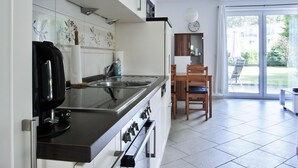 Een moderne keuken met een inbouwfornuis, een koffiezetapparaat en een spoelbak. Er is een eethoek met een tafel en stoelen.