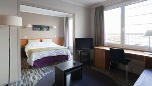 Hotellihuone, jossa on sänky, työpöytä, televisio ja tuoli.