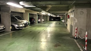Useita kerroksia sisältävä pysäköintihalli, jossa on betonipilarit, vihreä lattia ja valkoisilla viivoilla merkityt pysäköintipaikat.