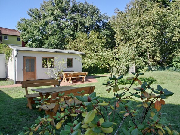 Un petit bâtiment d’un seul étage, doté d’une porte et de fenêtres en bois, avec une table de pique-nique et des bancs à l’avant.
