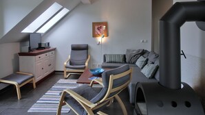 Een moderne loft slaapkamer met een schuine kap, dakraam, een ingebouwde heater, een bank, een stoel, een bureau en een nachtkastje.