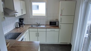 Een kleine keuken met een spoelbak, fornuis, magnetron en kastjes.