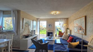 Una sala de estar acogedora con comedor, un sofá, un televisor y obras de arte en las paredes.