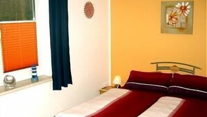 Un dormitorio con cama, ventana con persianas, mesita de noche y un adorno en la pared.