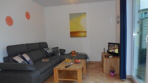 Una sala de estar con sofá, mesa de centro y televisor sobre un mueble de madera.