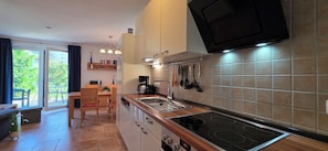 A modern kitchen with a built-in stove, a coffee maker, and a variety of utensils hanging on the wall. - 2-zimmer-fewo für bis 4 Pers. mit 2 Fahrrädern (Graal-Müritz)