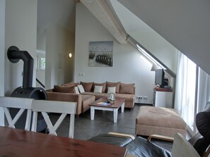 Een moderne woonkamer met een bank, een tafel, een open haard en een televisie.