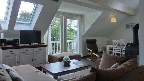 Ein gemütliches Wohnzimmer mit einer Couch, einem Couchtisch, einem Fernseher und einem Grill.