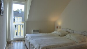 Ein Schlafzimmer mit Bett, Nachttisch, Lampe und Fenster.