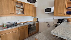 A kitchen with wooden cabinets, a microwave, a sink, and a stove.