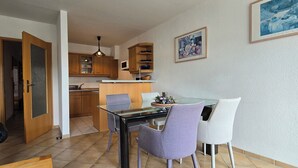 A modern kitchen with wooden cabinets, a dining table with chairs, and a kitchen island.