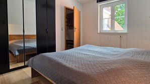 A bedroom with a bed, a wardrobe, a window, and a floor lamp.