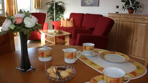 A dining area with a table set for four, including plates, cups, and a vase of flowers. - Strandnahe 3-zimmer-fewo im 3.og für 4 Pers. mit Wlan (Graal-Müritz)
