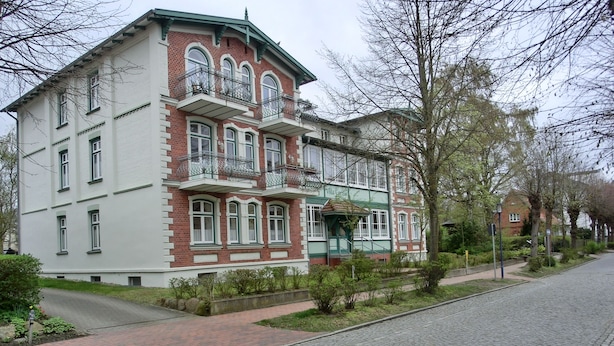 A two-story building with a green and white facade, multiple windows, and a balcony with a metal railing. - 2-zi-fewo für 4 Pers. mit Wlan, Haustiere Erlaubt (Graal-Müritz)