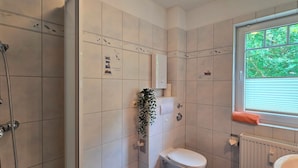 A bathroom with a shower, toilet, and window with a view of greenery. - 2-zimmer-fewo für 3 Pers. Inkl. Strandkorb (Graal-Müritz)
