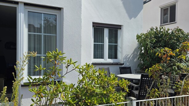 A white building with two windows, a door, and a small patio area with a table and chairs. - 2-zi.-fewo im EG mit Terrasse im Ortszentrum (Graal-Müritz)