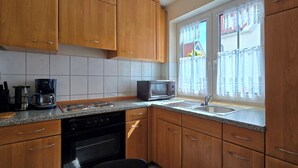 A kitchen with wooden cabinets, a microwave, a coffee maker, and a sink. - 2-zi.-fewo im EG mit Terrasse im Ortszentrum (Graal-Müritz)