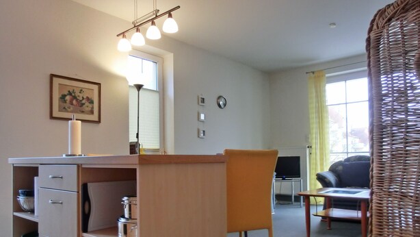 Een compacte leefruimte met een kitchenette, een eethoek en een zithoek met een televisie.