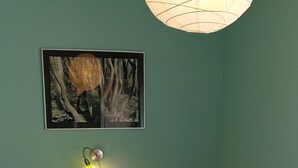 Cama bem arrumada com roupa de cama branca e três almofadas em quarto com paredes verde-água.