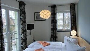 Habitación de hotel con dos camas, un televisor, un cuadro en la pared y una ventana con cortinas.