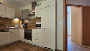 Een kleine keuken, voorzien van een vaatwasser, oven, magnetron en koffiezetapparaat.