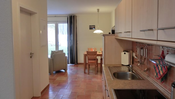 Cocina compacta con pileta, cocina y alacenas. Hay una zona de comedor con mesa y sillas.