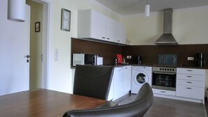 A compact kitchen with a washing machine, microwave, and coffee maker. - 3-zi.-fewo für 4+2 Personen - mit Telefon- und Internetanschluss (Graal-Müritz)