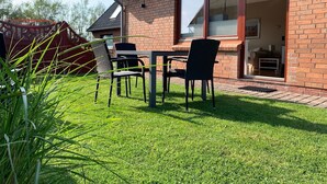 Une maison en briques avec un patio, une table et des chaises.
