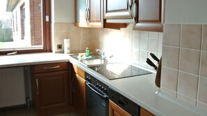 Une cuisine avec des meubles de rangement en bois, un lave-vaisselle, un évier et une fenêtre.