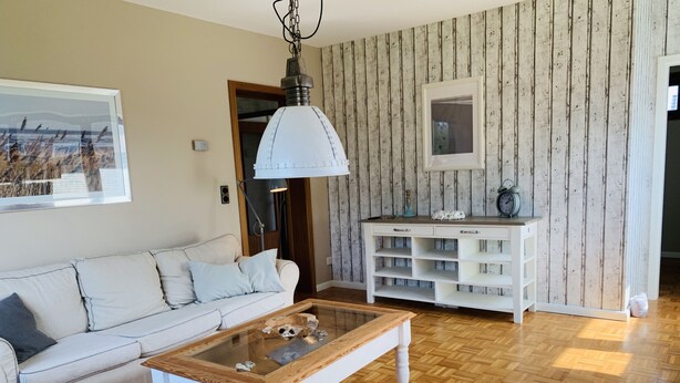 Un salon avec un canapé blanc, une table basse en bois et une console blanche dotée d’étagères.