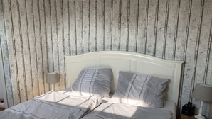 Un lit double avec une tête de lit blanche, deux oreillers et une table de chevet avec une lampe.