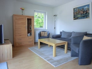 Un salon moderne avec un canapé gris, un meuble en bois, une table basse en bois et un tableau accroché au mur.