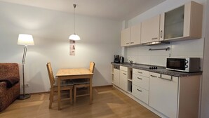 A compact kitchen with white cabinets, a microwave, and a dining area with a table and chairs. - Ruhige, Strandnahe 2-zimmer-ferienwohnung für 2 Pers. mit Balkon (Graal-Müritz)