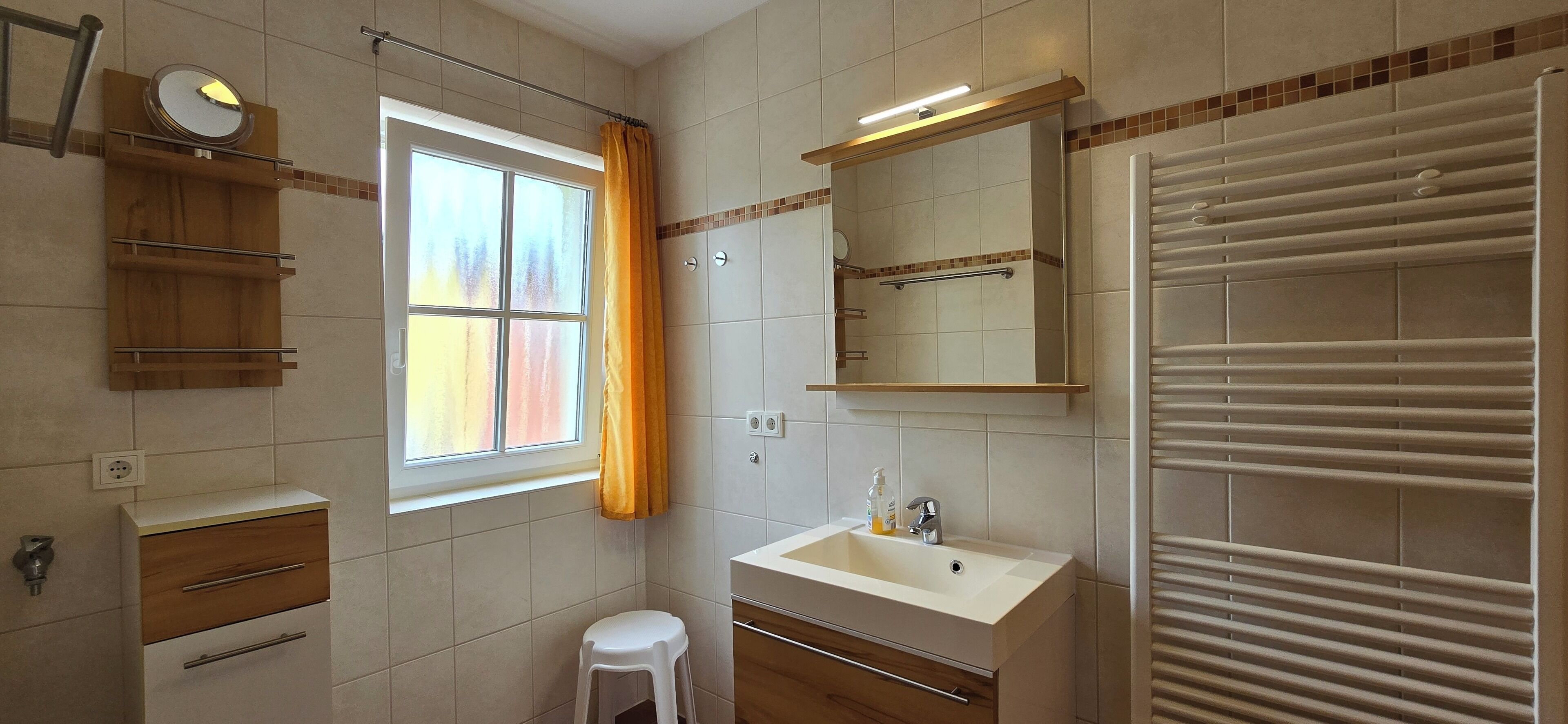 A bathroom with a window, a sink, a mirror, a towel rack, and a shower.