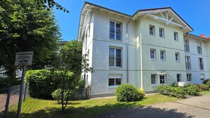 A multi-story building with a light facade, a sign indicating a private foundation, and a paved driveway. - Ruhige, Strandnahe 2-zimmer-ferienwohnung für 2 Pers. mit Balkon (Graal-Müritz)