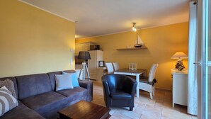 Un salon comprenant un canapé, des fauteuils, une table basse et un coin repas avec une table et des chaises.
