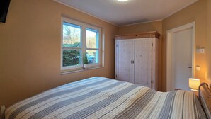 Une chambre à coucher avec un lit, une fenêtre, une armoire et un tableau au mur.