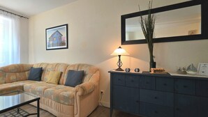 En stue med en sofa, et glasbord, en lampe, et skab og et billede i ramme på væggen.