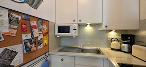 A kitchen with a microwave, sink, kettle, and coffee maker. - Strandnahe 2-zimmer-fewo im 1. OG für 3 Pers (Graal-Müritz)
