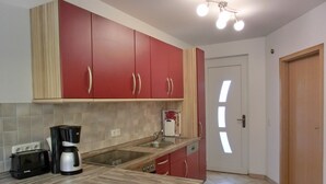 A kitchen with red cabinets, a wooden countertop, a coffee maker, and a toaster.