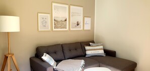 Ein Wohnzimmer mit einem braunen Sofa, einer Lampe und drei gerahmten Bildern an der Wand.