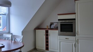 Une cuisine avec des armoires blanches, un plan de travail en bois et un four encastré.