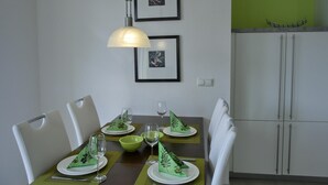 A dining area with a table set for four, chairs, a hanging light fixture, and framed pictures on the wall. - 3-zimmer-fewo für 4 Pers. im 1. OG (Graal-Müritz)